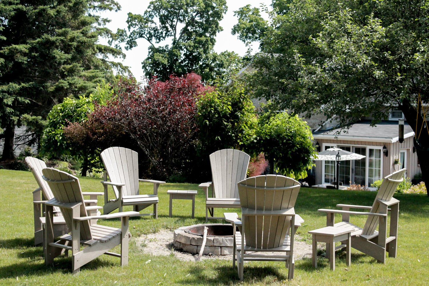 Firepit surrounded by Adirondack Chairs in the backyard gardens of Huntingdon House B&B in Stirling, Ontario