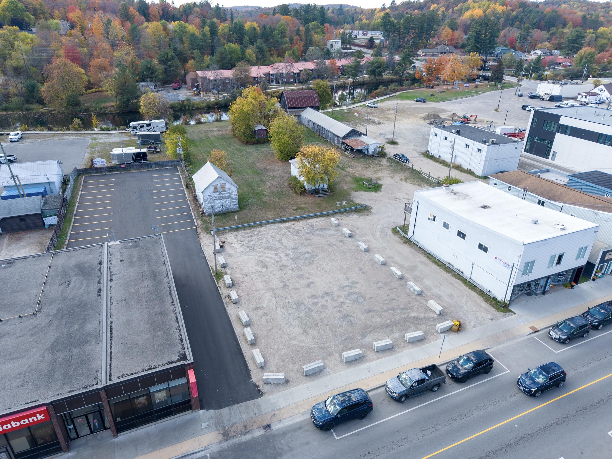 Vacant land with cars on a road and trees in the background. 