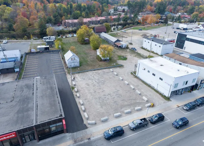 Vacant land with cars on a road and trees in the background. 