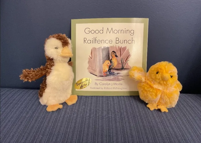 Two stuffed ducks with a railfence bunch book in the middle